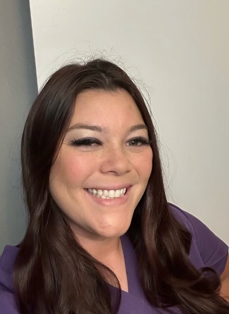 Portrait of a Leash and Lather groomer in purple scrubs, smiling